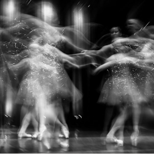A photograph of dancers at a long exposure to show movement and emotion. 