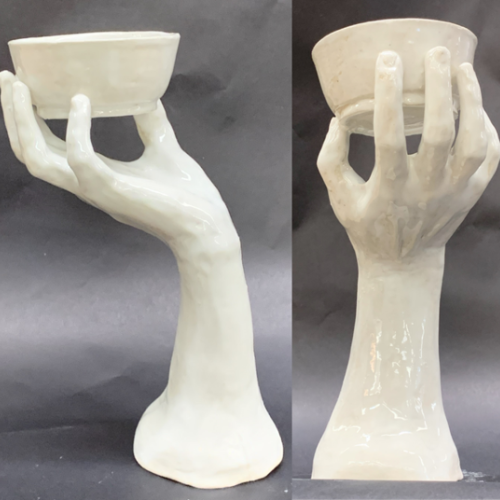 Ceramic clay creation of a hand holding a bowl painted white