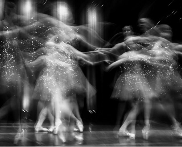 A photograph of dancers at a long exposure to show movement and emotion. 
