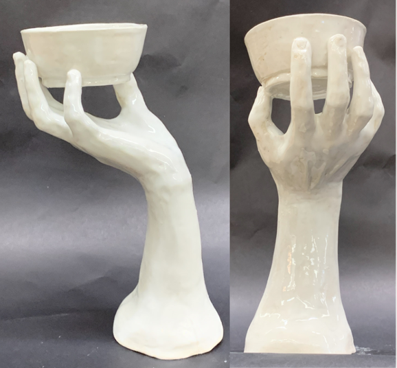 Ceramic clay creation of a hand holding a bowl painted white